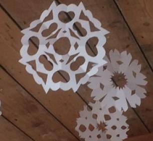paper snowflakes hanging from the wooden ceiling of the zedshed